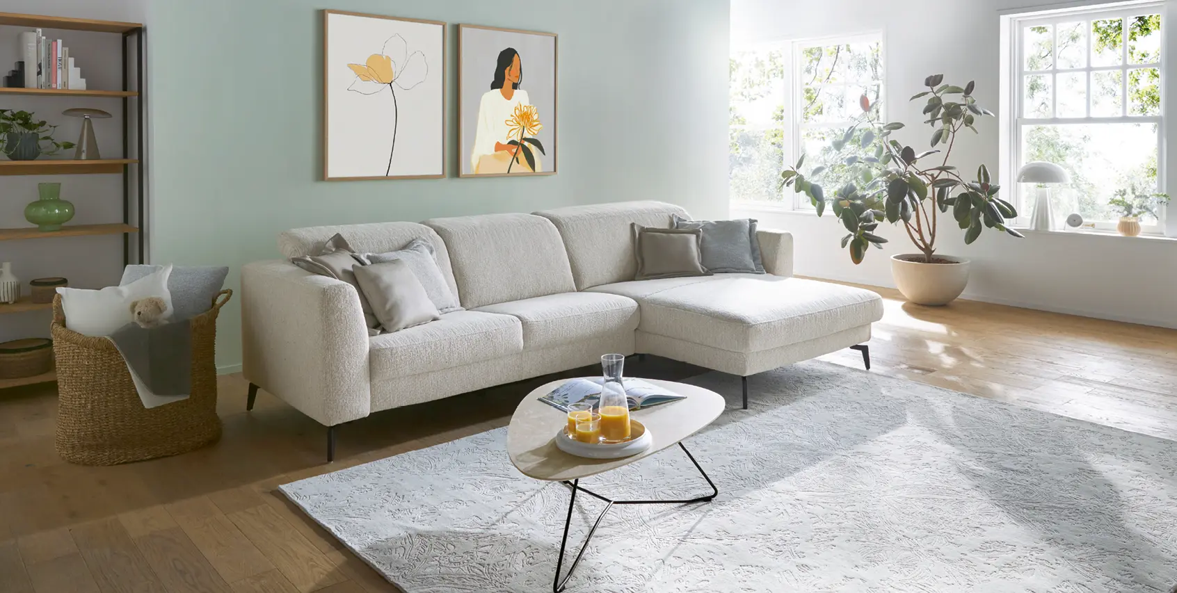 Helles Wohnzimmer mit modernem Ecksofa in Beige, großem Teppich und Couchtisch. Freundliche Einrichtung mit Pflanzen, Tageslicht und ruhigen Farben für ein gemütliches und stilvolles Wohnen.